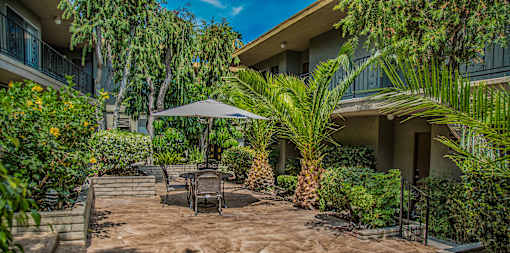 a patio with a table and chairs in front of a building