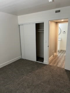 a room with a carpeted floor and a doorway to a bathroom