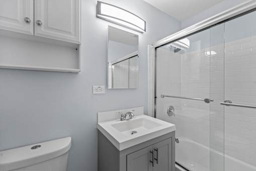 A white bathroom with a sink, mirror, and bathtub.
