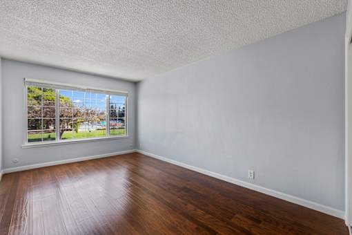 A room with a window showing a view of a house and trees.