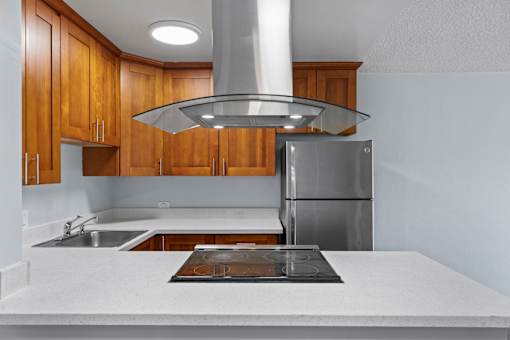 A modern kitchen with wooden cabinets and a stainless steel refrigerator.