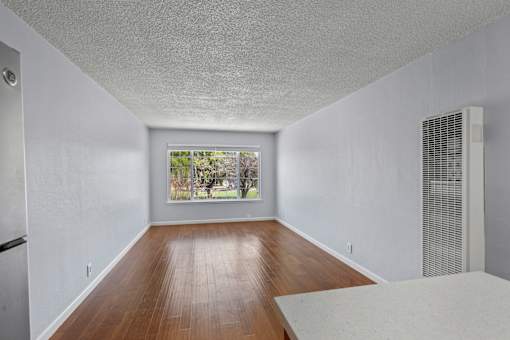 A room with white walls and a window with a view of trees.