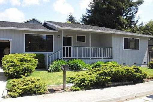 A house with a grey roof and a white wall with a small porch.