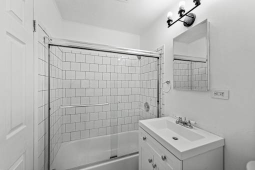 A white bathroom with a tiled shower and sink.