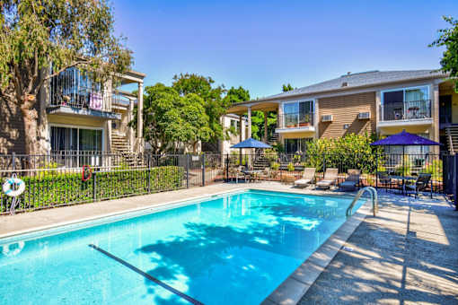 A swimming pool surrounded by a fence and chairs.