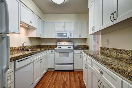 A kitchen with white cabinets and a granite countertop.