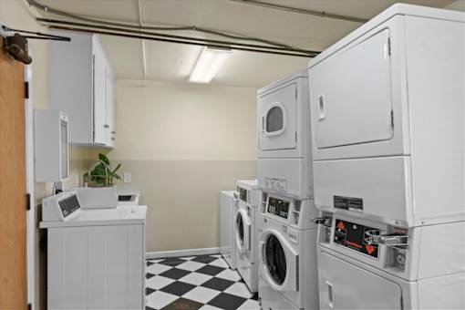 A laundry room with a checkered floor and a washer and dryer stacked on top of each other.