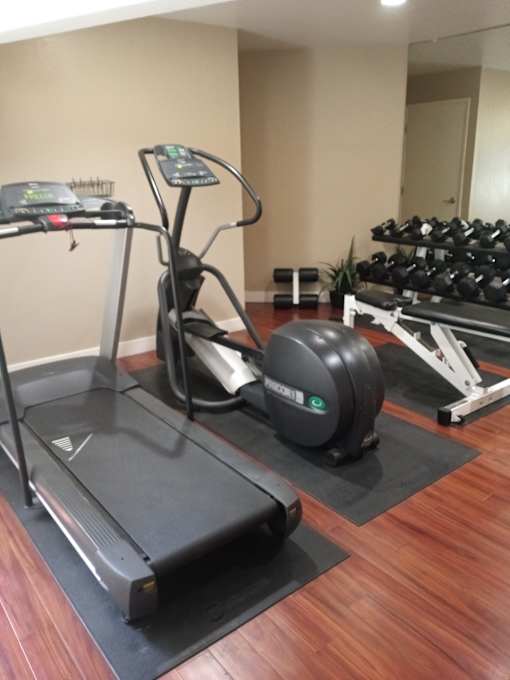 A treadmill, a rowing machine, and a stationary bike are in a gym.