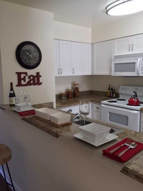 A kitchen with a counter top and a clock on the wall.