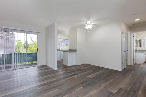 an empty living room with a large window and a ceiling fan