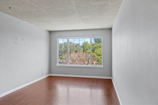 Empty room with a window overlooking a tree-filled landscape.