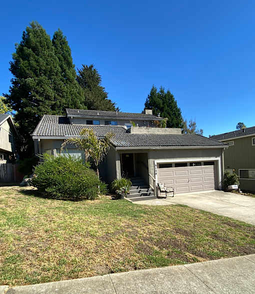 A house with a grey garage door and a brown roof.