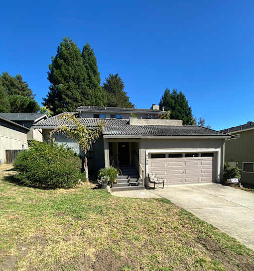 A house with a grey garage door and a brown roof.