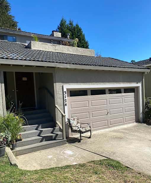 A house with a grey garage door and a bicycle parked outside.