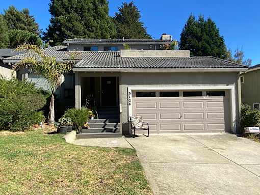 A house with a grey garage door and a black roof.