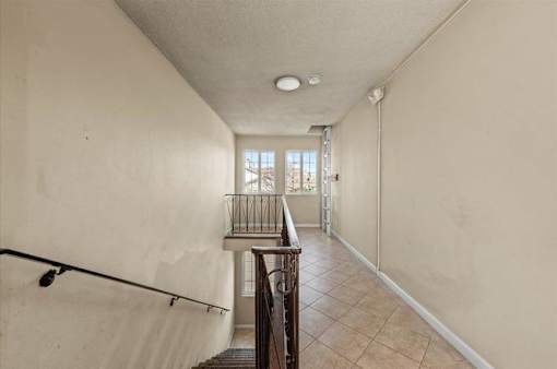 A long hallway with a staircase and a balcony.