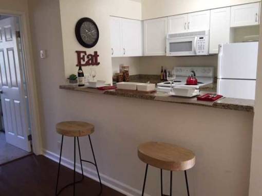 A kitchen with a white refrigerator, a microwave, and a counter with a red object on it.