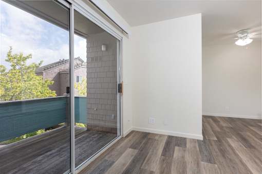 an empty living room with a sliding glass door to a balcony