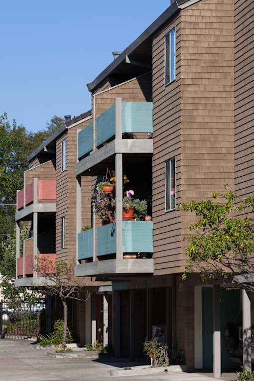 a large brown apartment building with green balconies in the daytime and potted plants