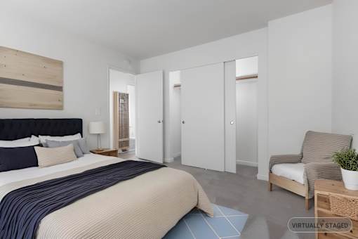 A bedroom with a bed, chair, and wardrobe.