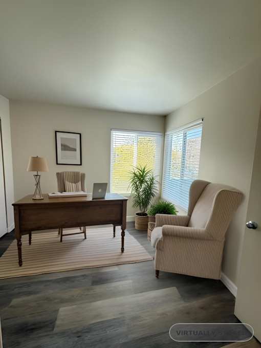 A room with a desk, chair, and potted plant.