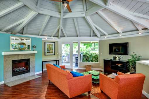 A living room with a fireplace and two orange chairs.