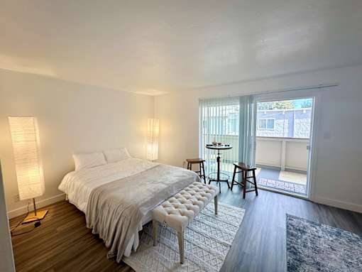 a bedroom with a bed and a sliding glass door to a balcony