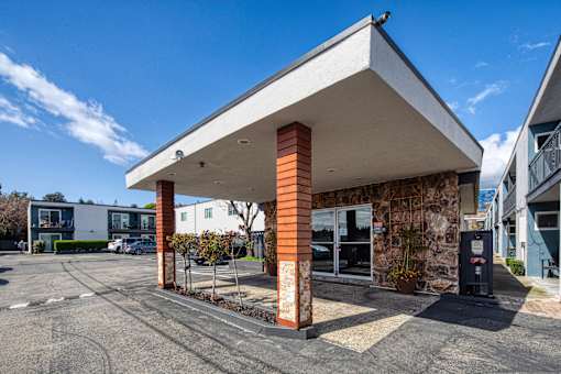 A parking lot with a building featuring a white and orange pillar.