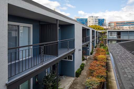 A long balcony with a metal railing and a blue wall.
