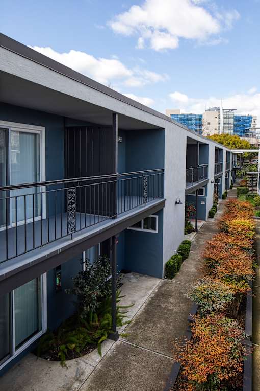 A long row of blue and white buildings with balconies and plants in front.