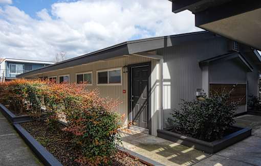 A modern building with a grey exterior and a brown door.