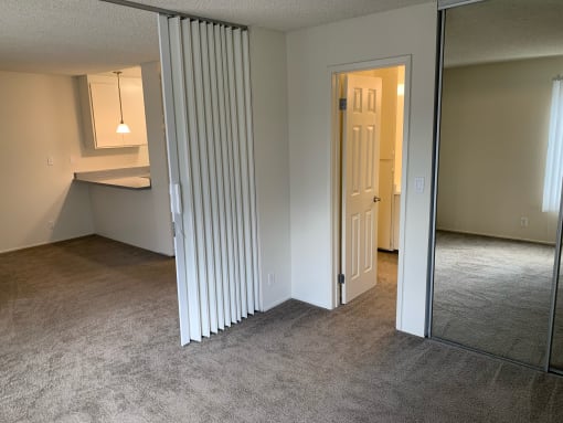 a living room with a mirrored closet and an open door