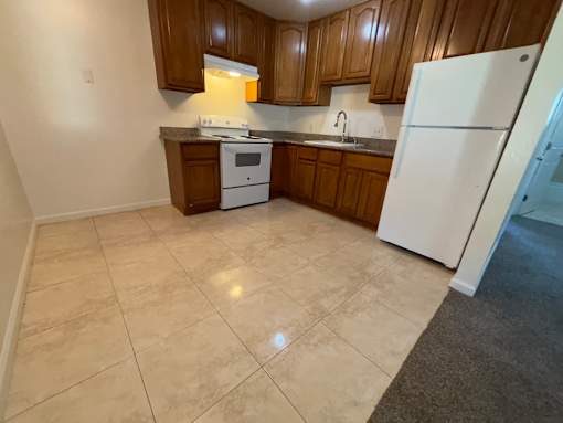 A kitchen with white appliances and wooden cabinets.