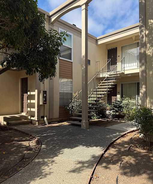 A beige two-story house with a staircase leading to the second floor.