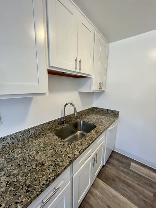a kitchen with white cabinets and granite counter top and a sink