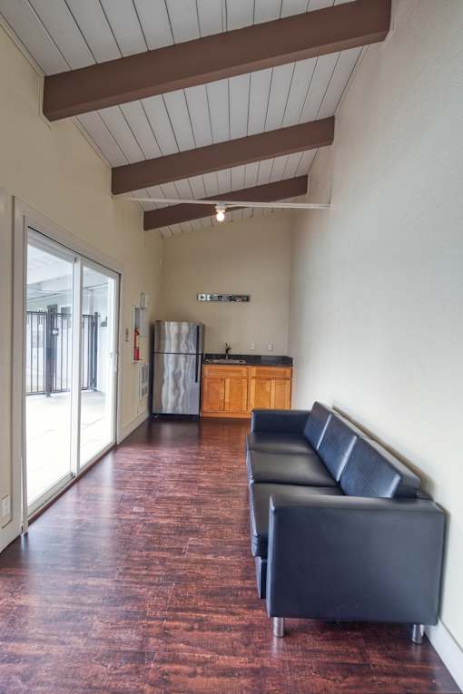 A black leather couch sits in a room with a wooden floor.