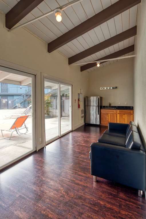 A black leather couch sits in a room with wooden floors and a ceiling with wooden beams.