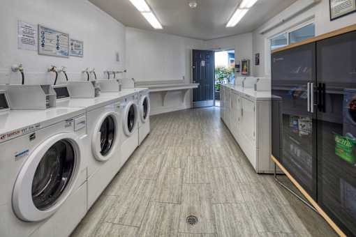 A laundromat with washers and dryers lined up.