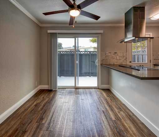 A room with a ceiling fan and sliding glass doors.