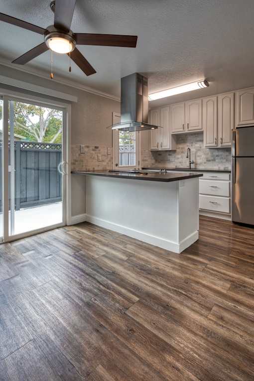 A kitchen with a wooden floor and a ceiling fan.