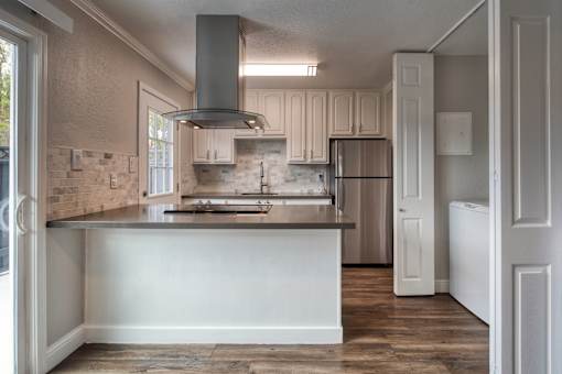 A kitchen with a refrigerator and a stove top oven.