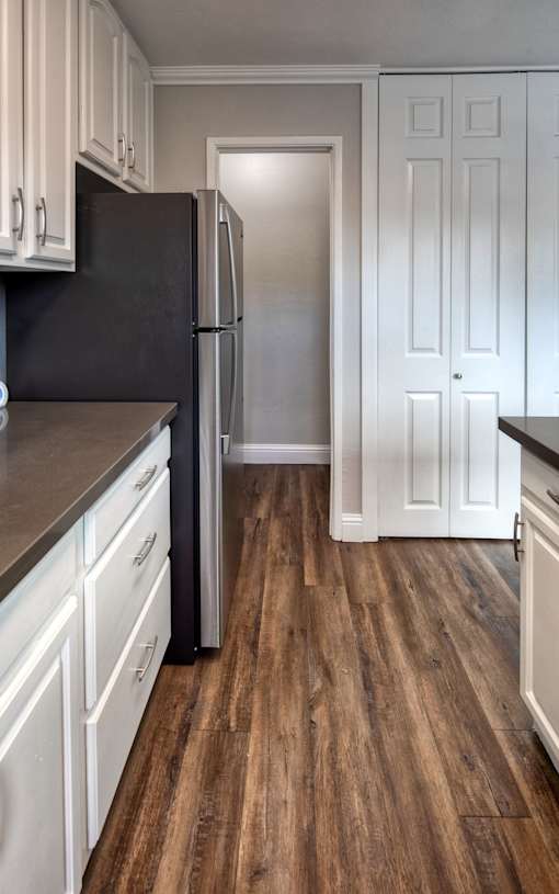 A kitchen with a black fridge and white cabinets.