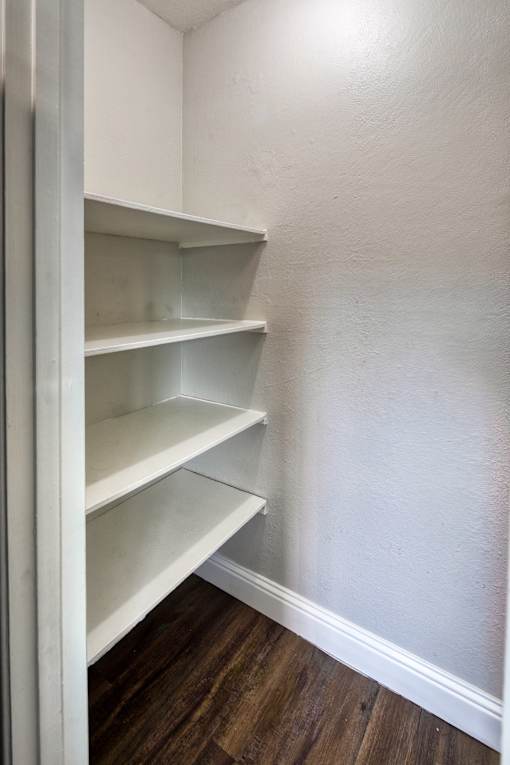 A white empty pantry with wood floors and white walls.