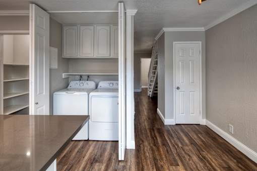 A kitchen with white appliances and wooden floors.