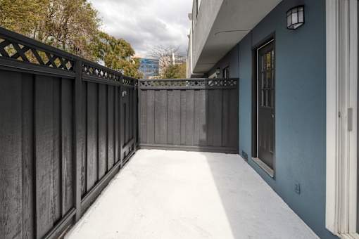 A balcony with a black railing and a blue wall.