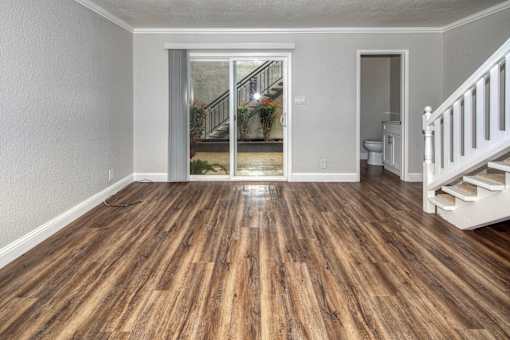 A room with wooden floors and a staircase leading to a balcony.
