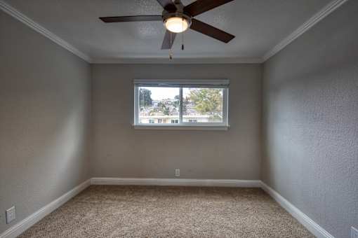 A room with a ceiling fan and a window.