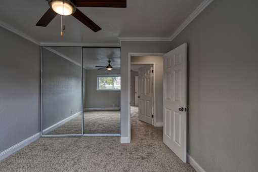 A room with a ceiling fan and a sliding glass door.