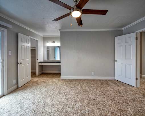A room with a ceiling fan and carpeted floor.