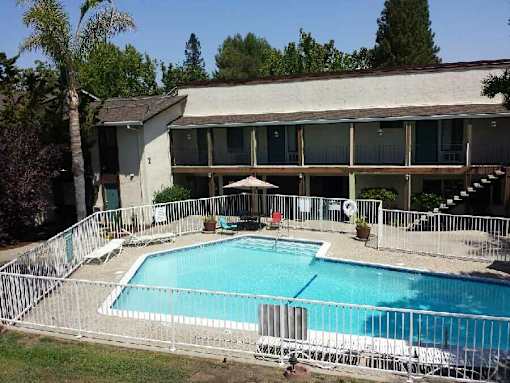 A pool surrounded by a fence with a building in the background.